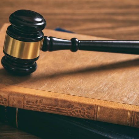 Law gavel on law books, wooden desk, dark background